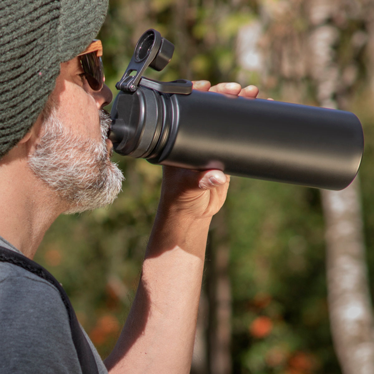 Persona en un bosque bebiendo de una botella térmica king