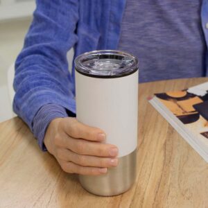 Persona apoyando un mug nori de color blanco sobre una mesa de madera