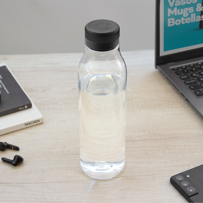 Botella de plástico transparente con tapa a rosca color negro mate con anillo de silicona color negro sobre escritorio.