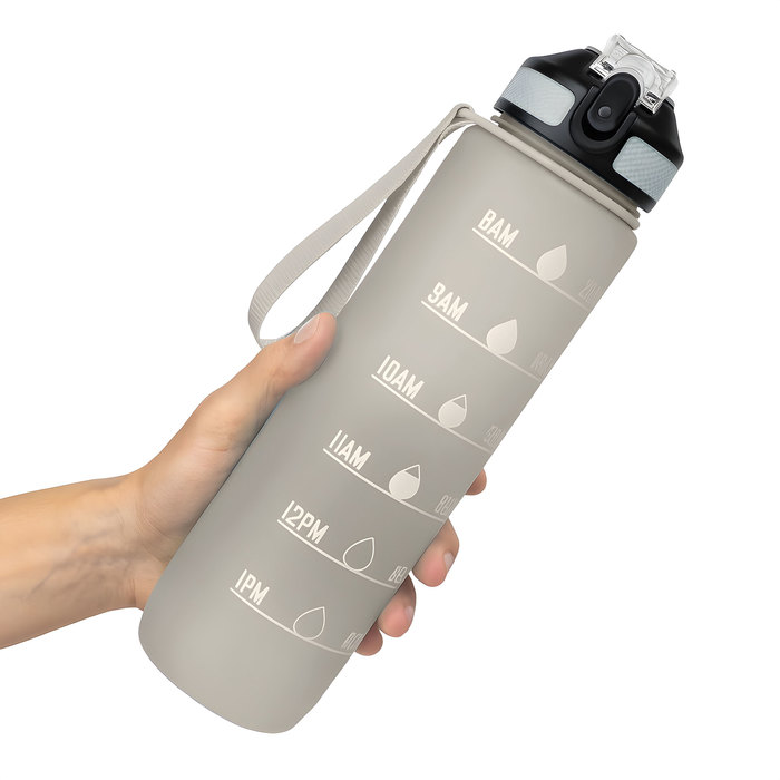 Mano sosteniendo una botella deportiva motivacional NADAL en color gris con acabado frost, con contador de tiempo, tapa con boquilla rebatible y correa
