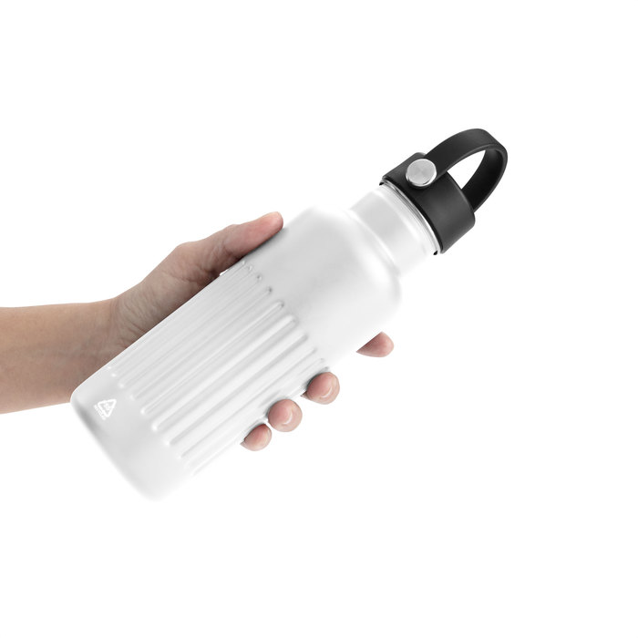 Mano sosteniendo la botella térmica KAWA de acero inoxidable color blanco , con cuerpo con bajorrelieve para mejor agarre y su tapa negra con asa.